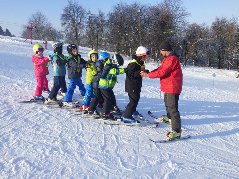 lyžařský instruktor při výcviku skupiny dětí